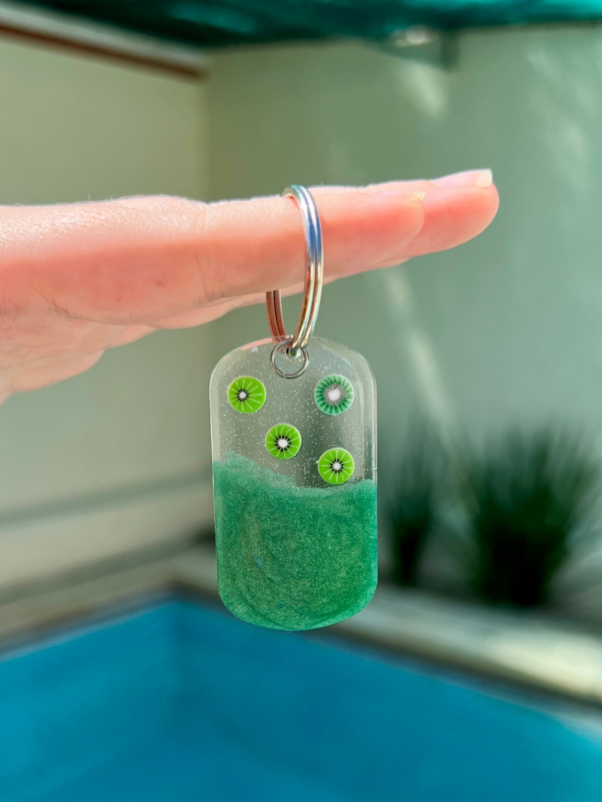 Placa rectangular verde con kiwi brillantes y gancho metálico. Diseño frutal para perro.