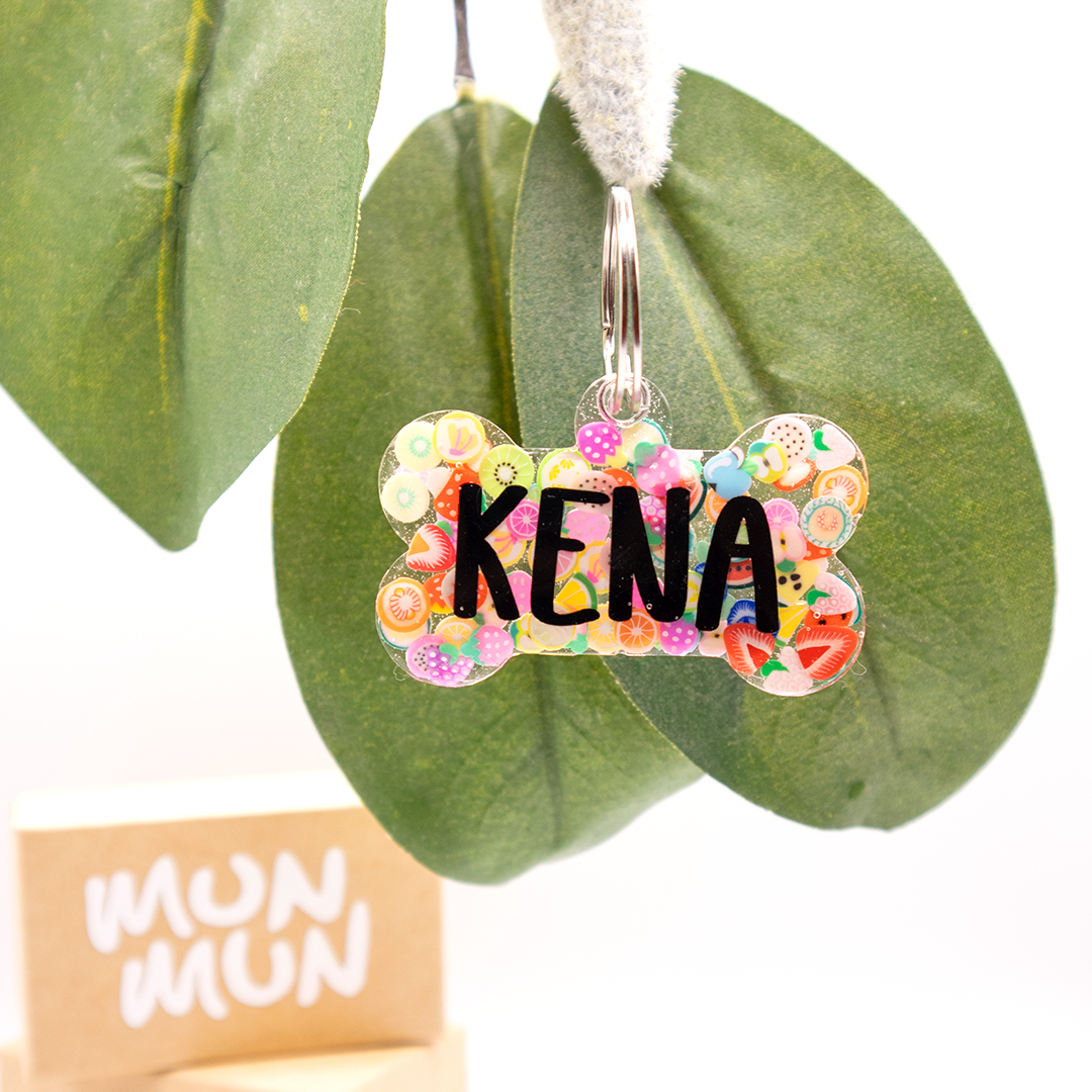 Placa en forma de hueso con frutas con nombre Kena. Accesorio único para perros.