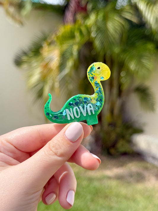 Placa verde con forma de dinosaurio y nombre Nova. Diseño divertido y personalizado.