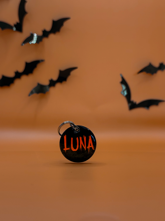 Placa redonda negra  y nombre “Luna” en rojo, perfecta para la noche de brujas.