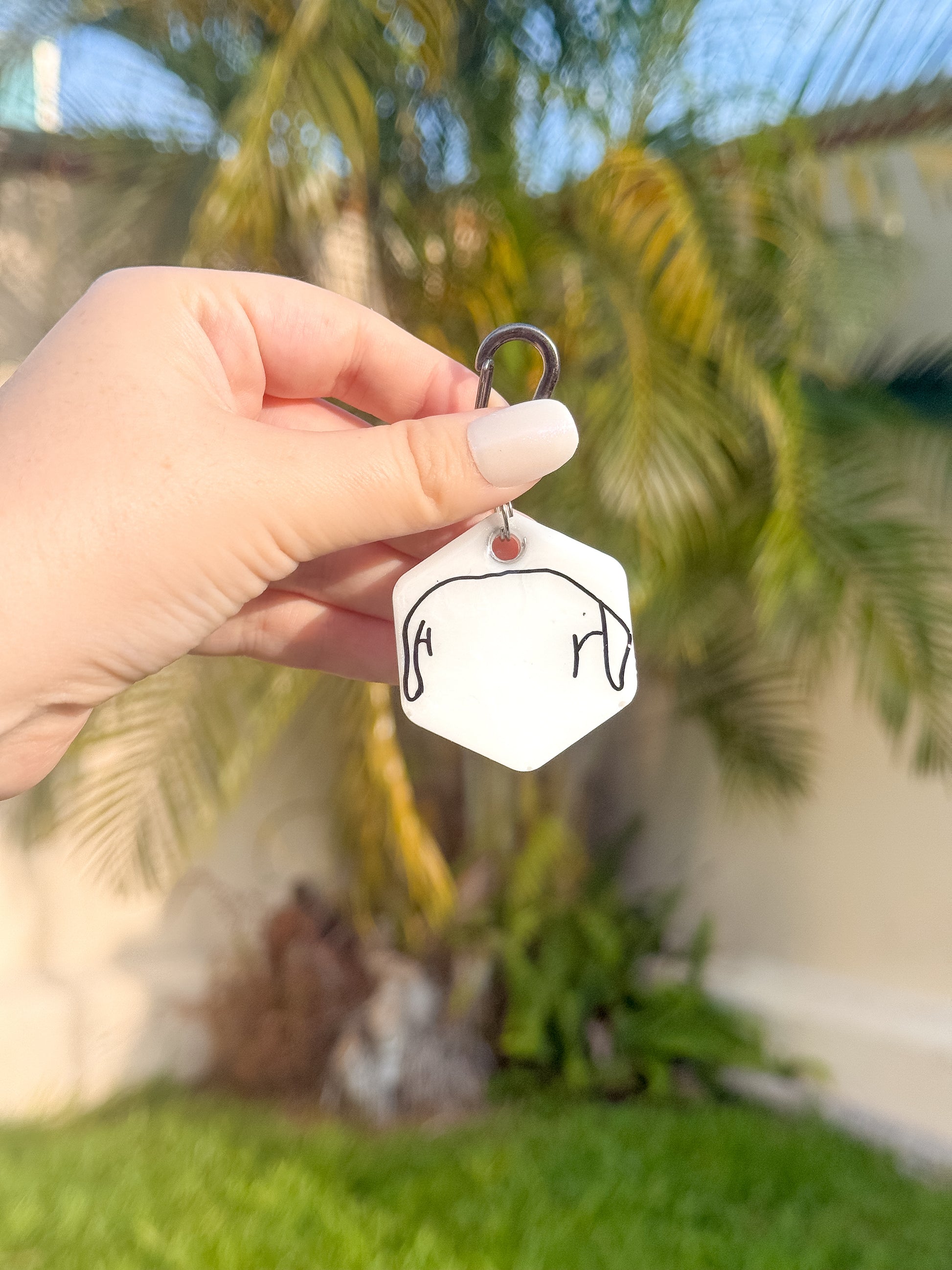 Placa con forma de hexagono blanca con línea negra, diseño original ideal para collares o llaveros.