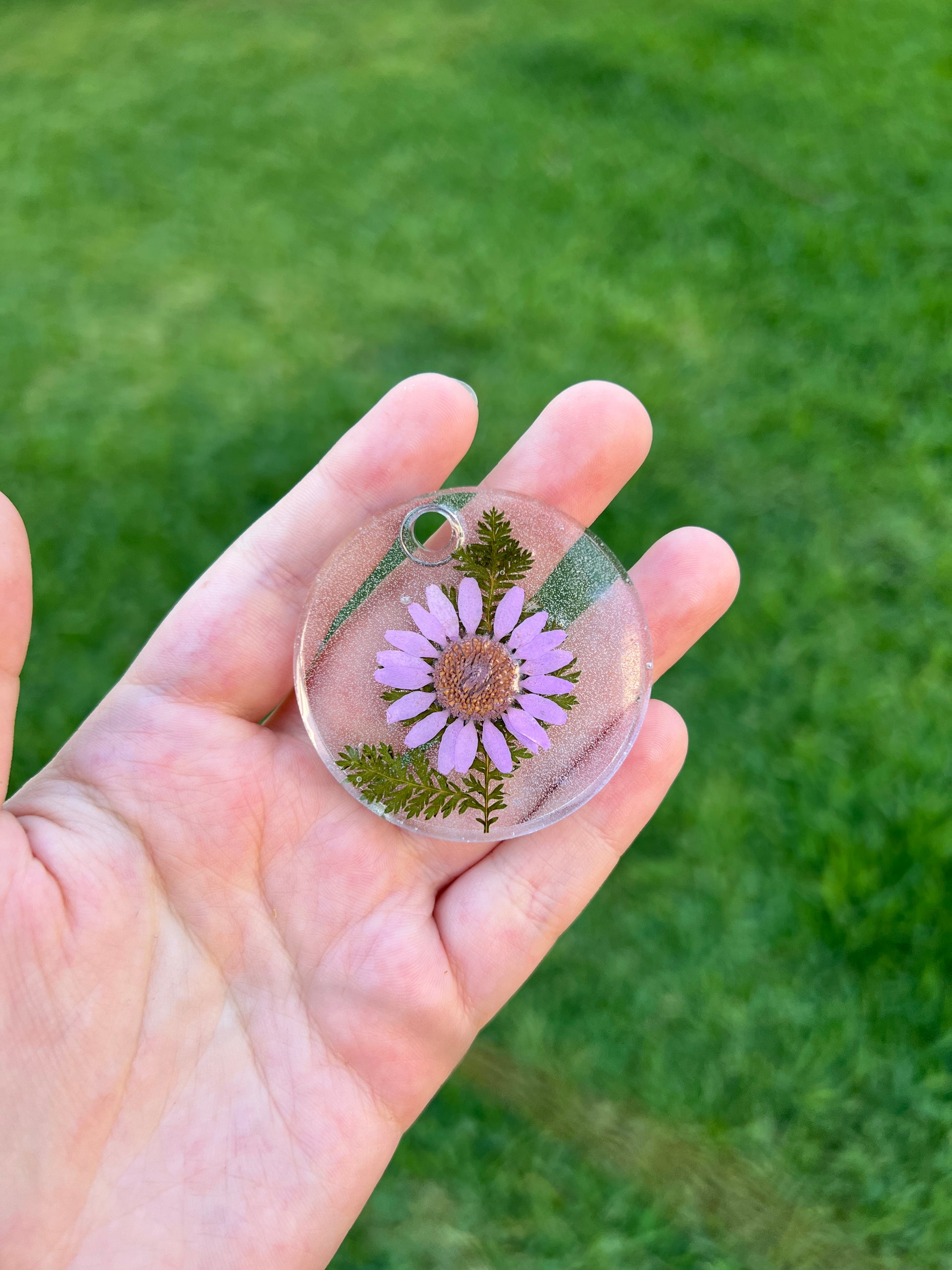 Placa redonda con flor prensada y fondo rosa. Diseño natural para mascotas.