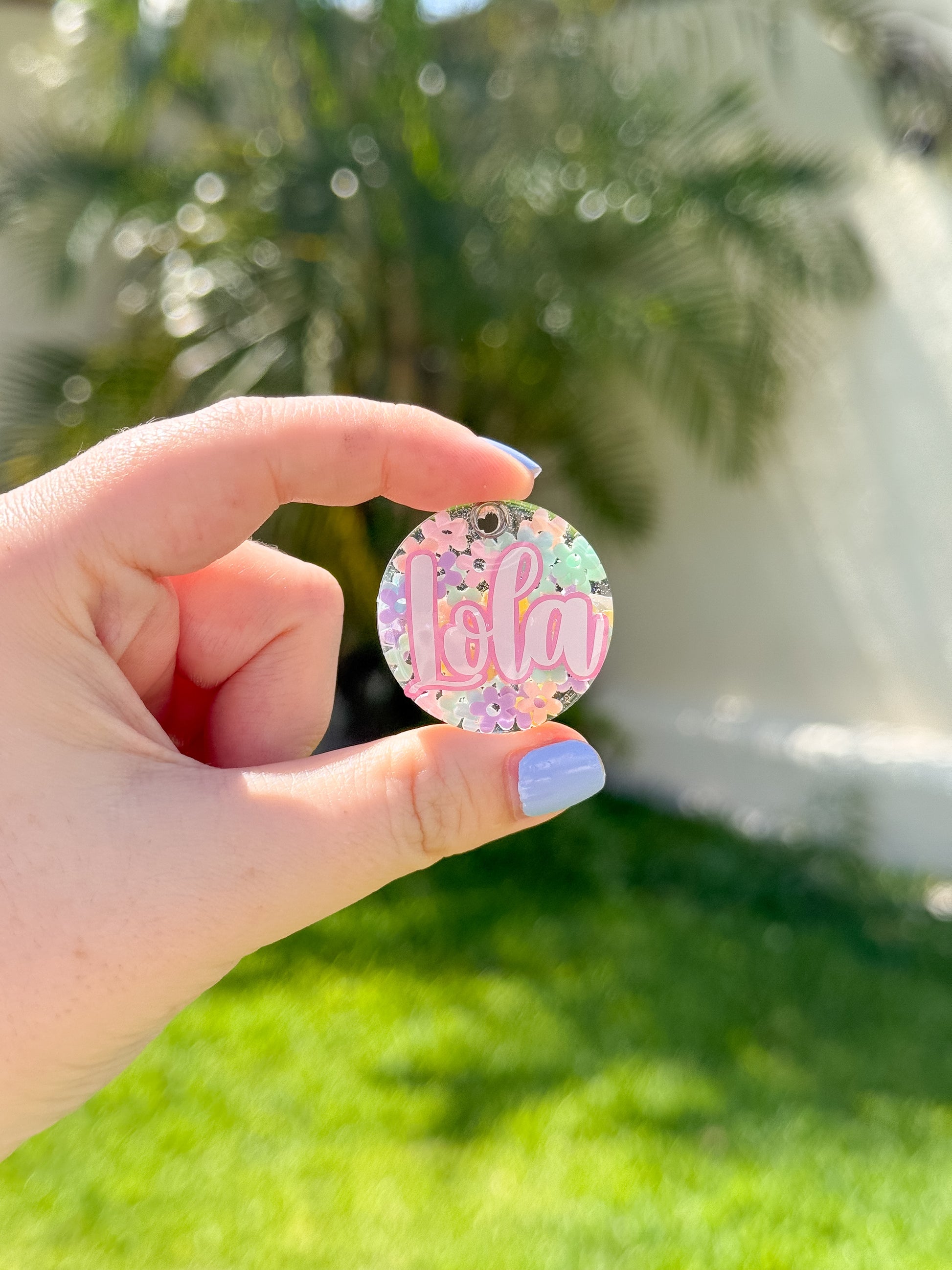 Placa redonda con fondo floral y nombre Lola. Diseño colorido y primaveral para mascotas.