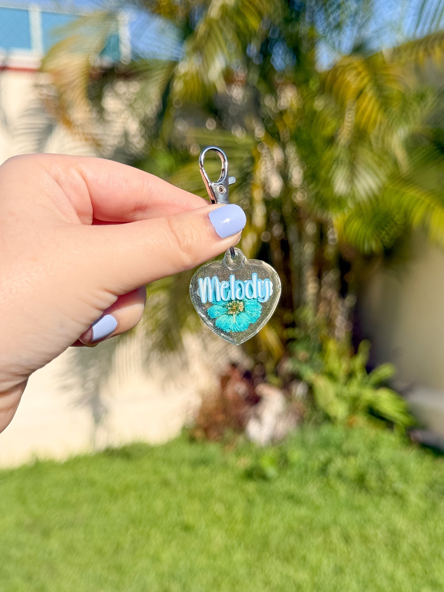 Placa en forma de corazón con flor prensada y nombre. Ideal para dueños que aman los detalles naturales y hechos a mano.
