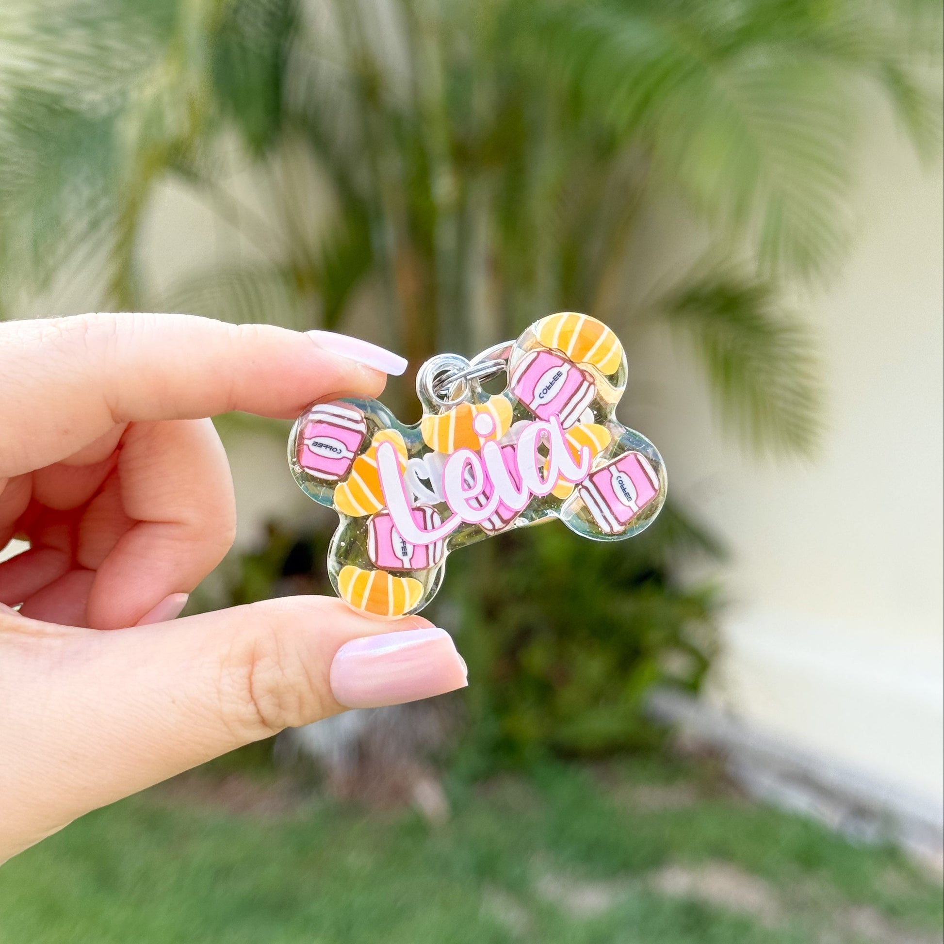 Placa en forma de hueso decorada con figuras de café y croissants, nombre “Leia”. Perfecta para doglovers que aman el desayuno.