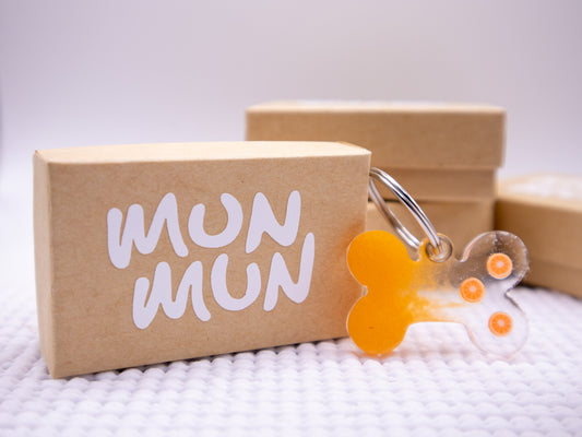 Placa naranja con forma de hueso con detalles blancos, en empaque Munmun. Estilo vibrante.