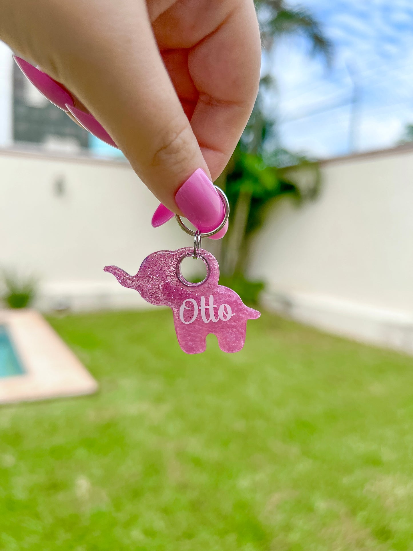 Placa para perro con forma de elefante color rosa glitter, personalizada con el nombre “Otto”. Hecha en resina ligera y durable, ideal para mascotas pequeñas con estilo.