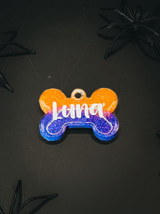 Placa en forma de hueso color morado y naranja con nombre Luna. Accesorio festivo de Halloween.