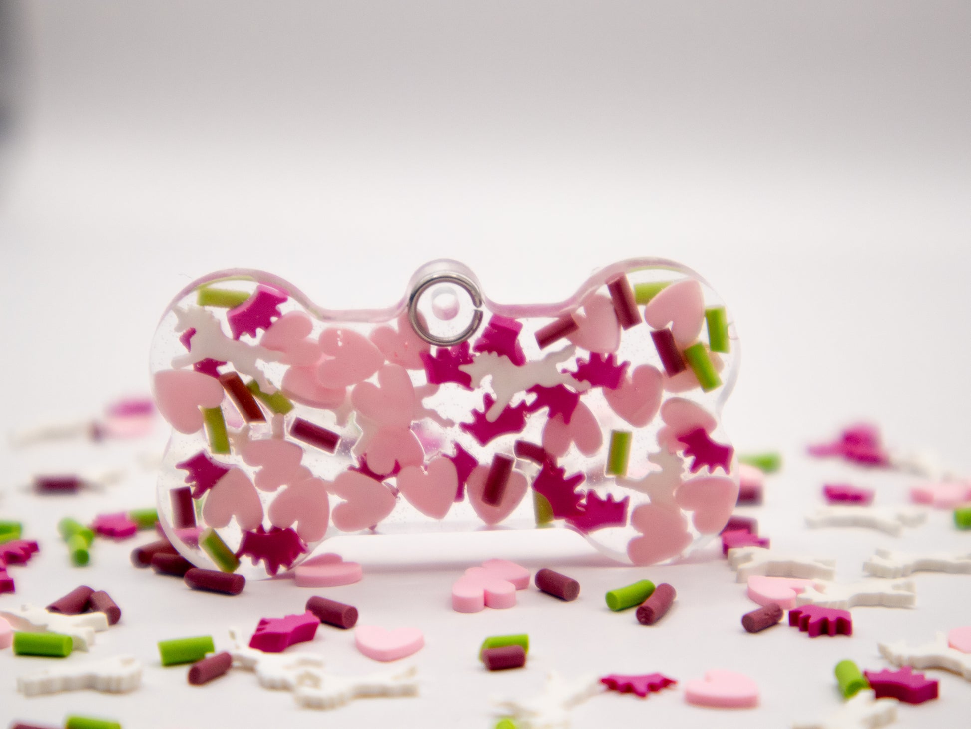 Placa con forma de hueso y corazones rosas y verdes. Estilo floral y romántico.