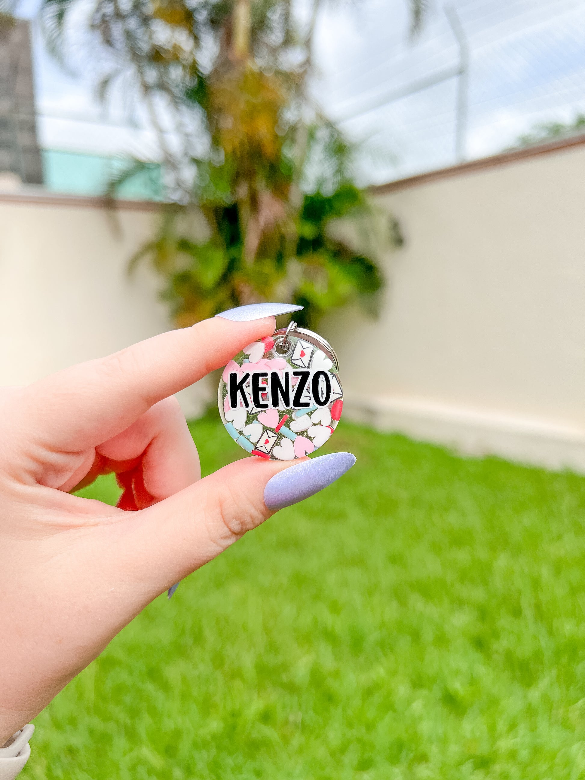 Placa redonda personalizada con nombre Kenzo. Fondo claro con corazones y vinil negro