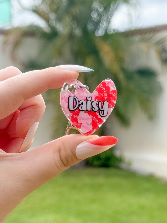 Placa en forma de corazón con fondo rojo y nombre “Daisy”, estilo dulce y amoroso para mascotas consentidas.
