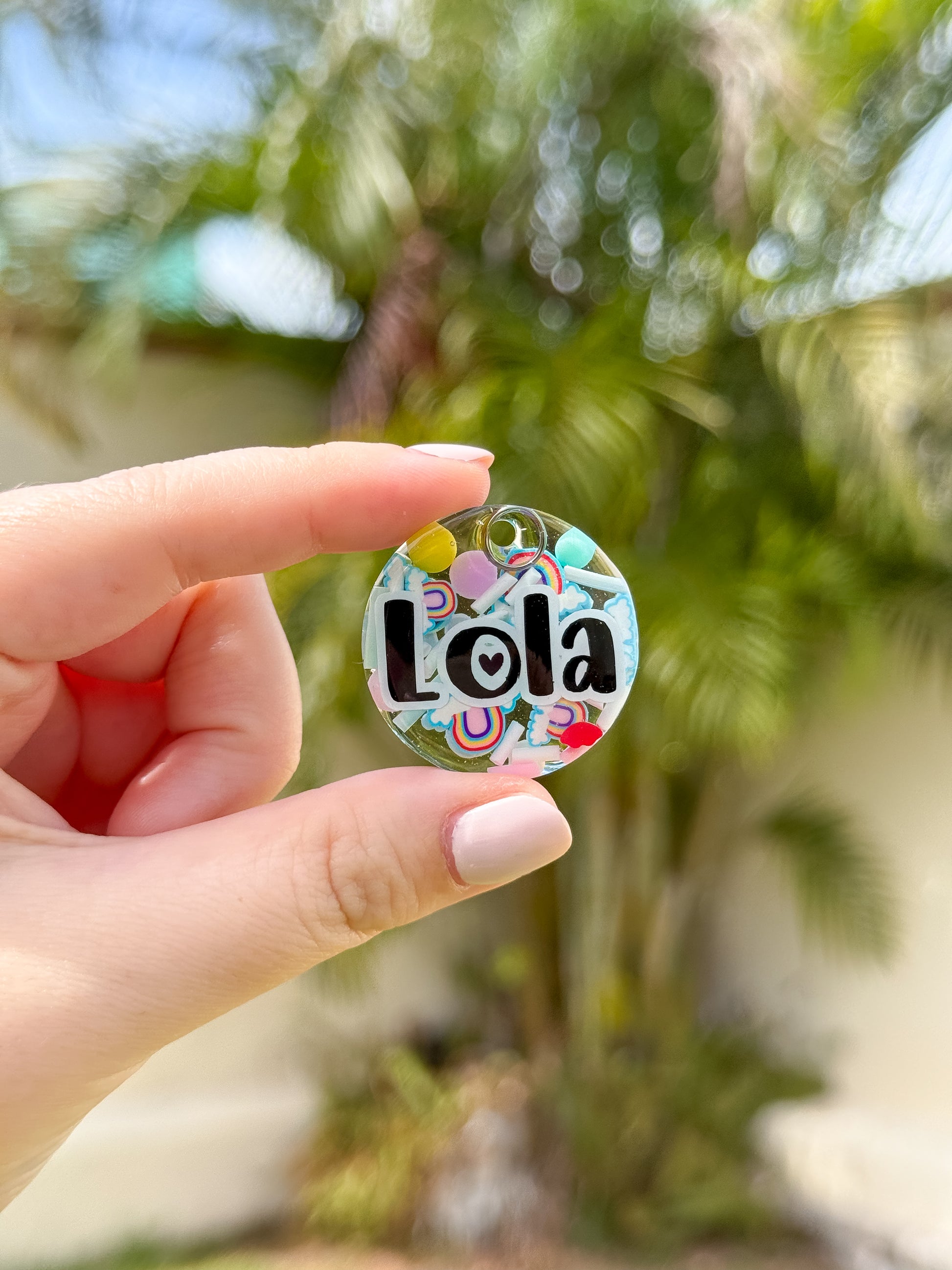 Placa redonda con fondo blanco y hojas verdes con nombre Lola. Estilo tropical y brillante.