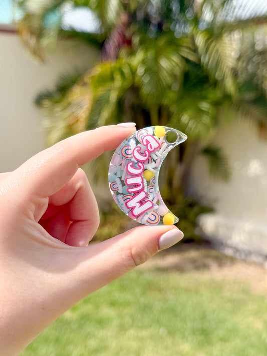 Placa en forma de luna con glitter rosa y nombre mucca. Accesorio personalizado y original.