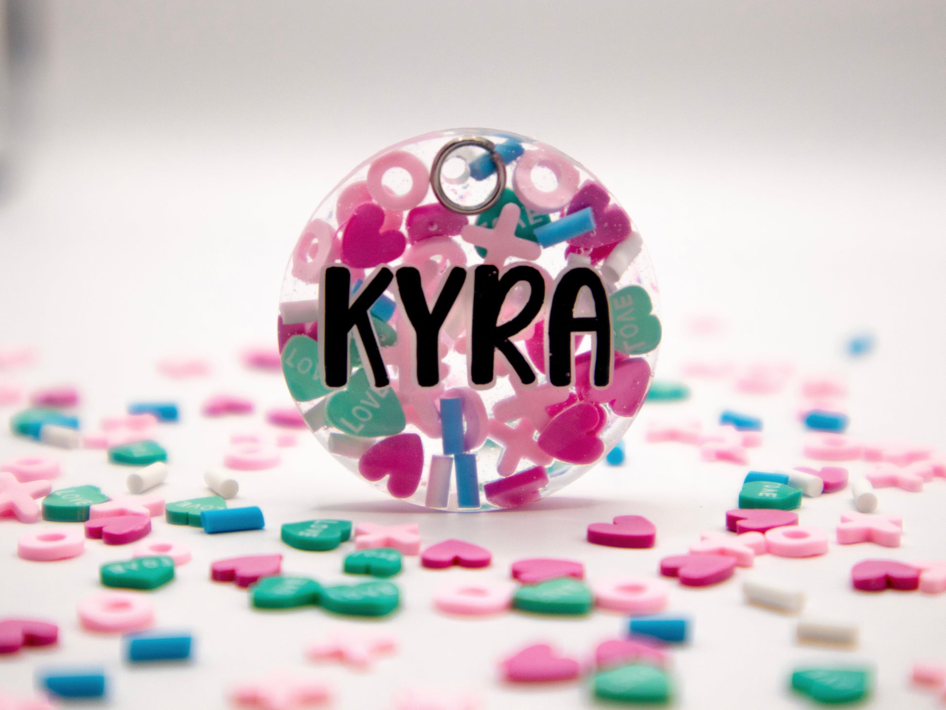 Placa redonda con nombre Kyra y fondo rosa con puntos. Diseño femenino y alegre.