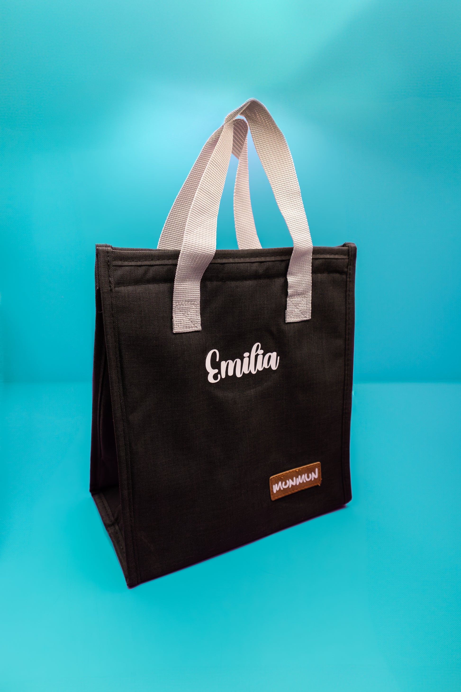 lonchera negra con asas grises y nombre personalizado Emilia. Práctica y personalizada