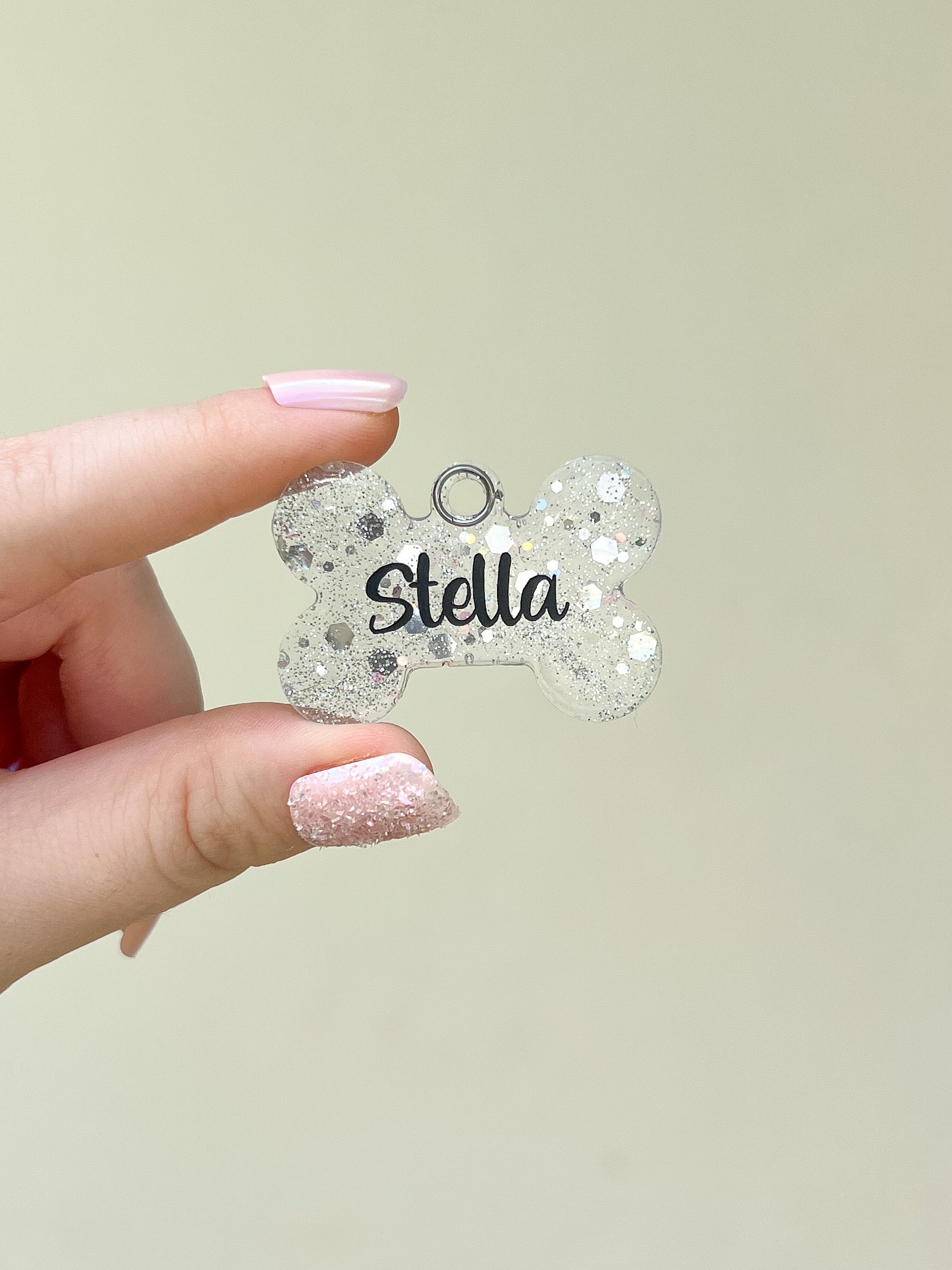 Placa de resina en forma de hueso blanco con glitter y nombre “Stella”. Diseño brillante para perritas con estilo.