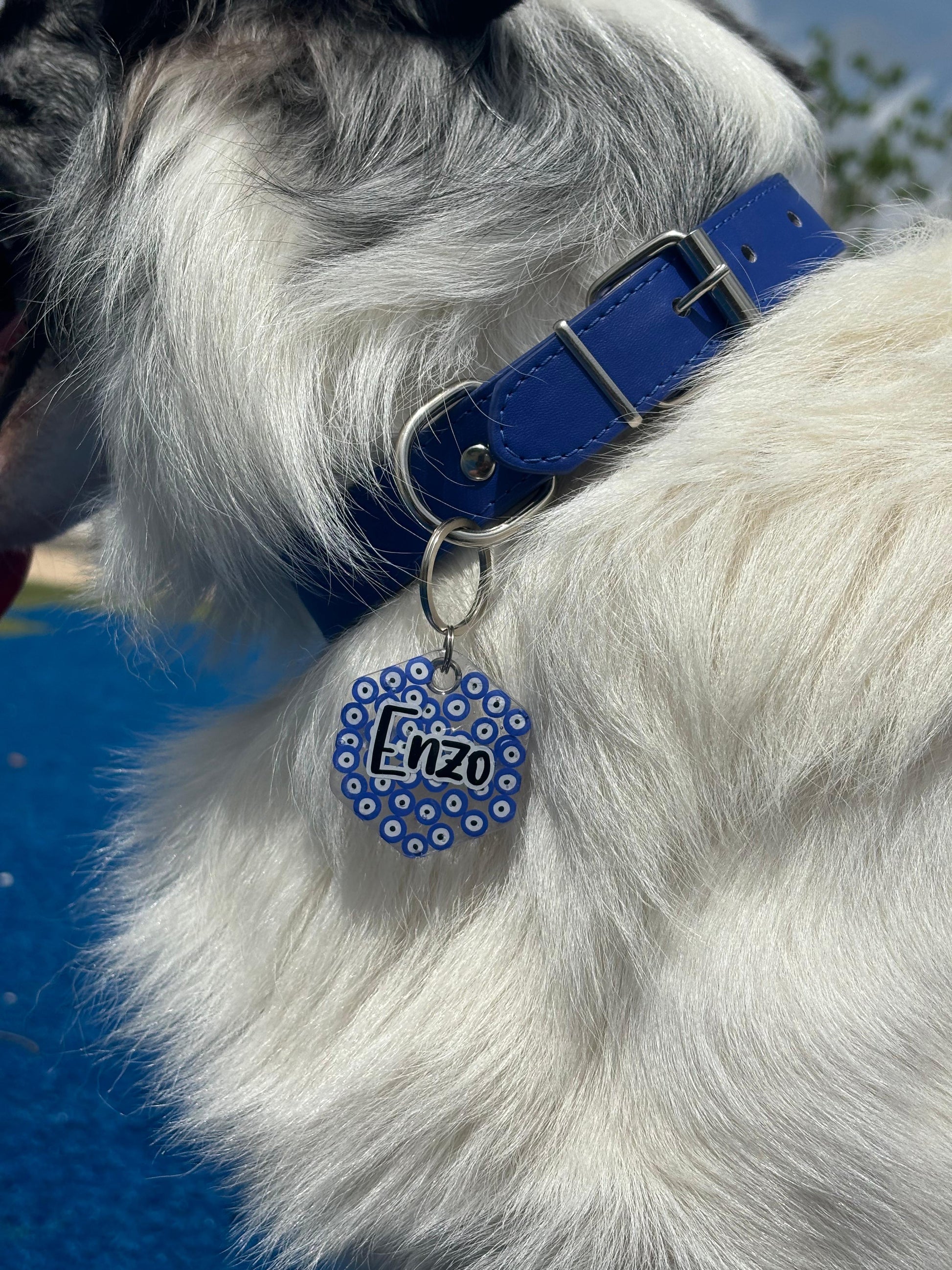 Placa redonda colgando de collar azul con diseño de ojo turco. Detalle protector y decorativo.