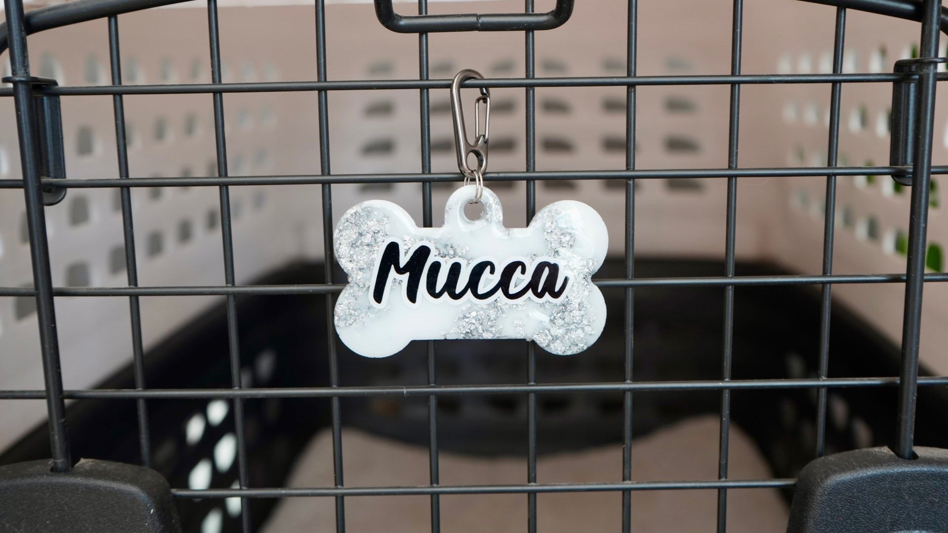 Placa metálica en forma de hueso con nombre Mucca. Ideal para transportadoras o collares