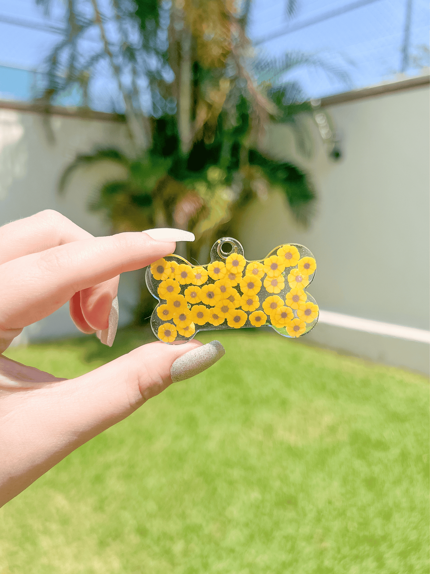 Placa amarilla en forma de hueso con patrón de margaritas. Accesorio personalizado con estilo floral.