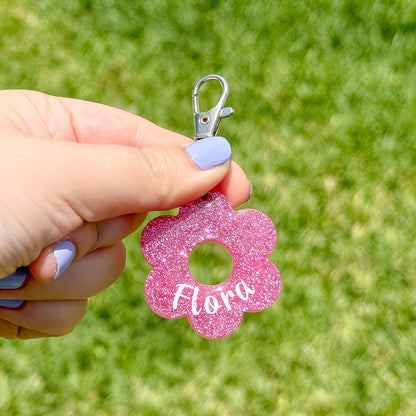 Placa de flor rosa intensa con glitter y nombre “Flora”. Estilo llamativo para mascotas únicas.

