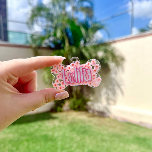 Placa en forma de hueso decorada con flores tipo cherry y nombre “Lolita”. Diseño dulce y femenino para perritas.