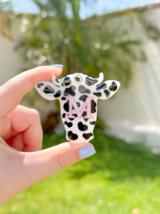 Placa con forma de vaquita en patrón blanco con negro, original y perfecta para perros únicos.