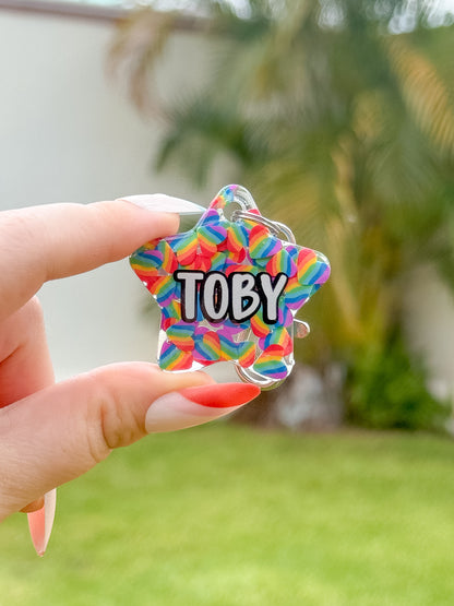 Placa en forma de estrella con nombre “Toby” y diseño de chispas de colores, perfecta para perros alegres y juguetones.