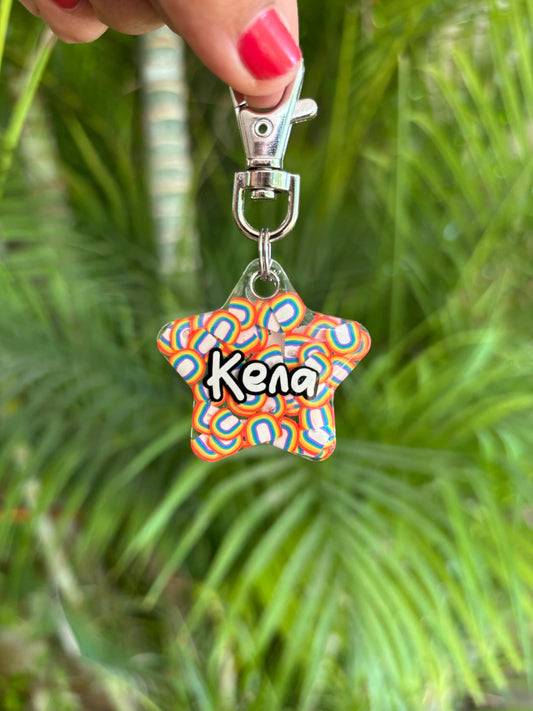 Placa con forma de estrella con arcoiris con nombre “Kena”, diseño abstracto con gancho giratorio.